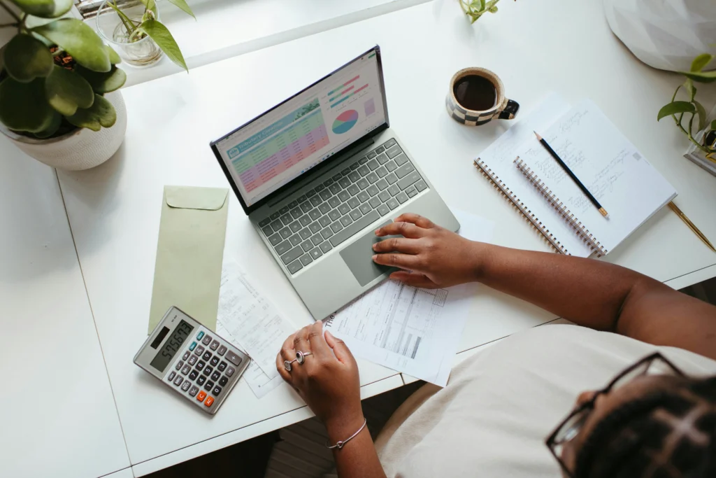 pessoa sentada em uma mesa com um laptop e uma calculadora organizando as finanças da microempresa