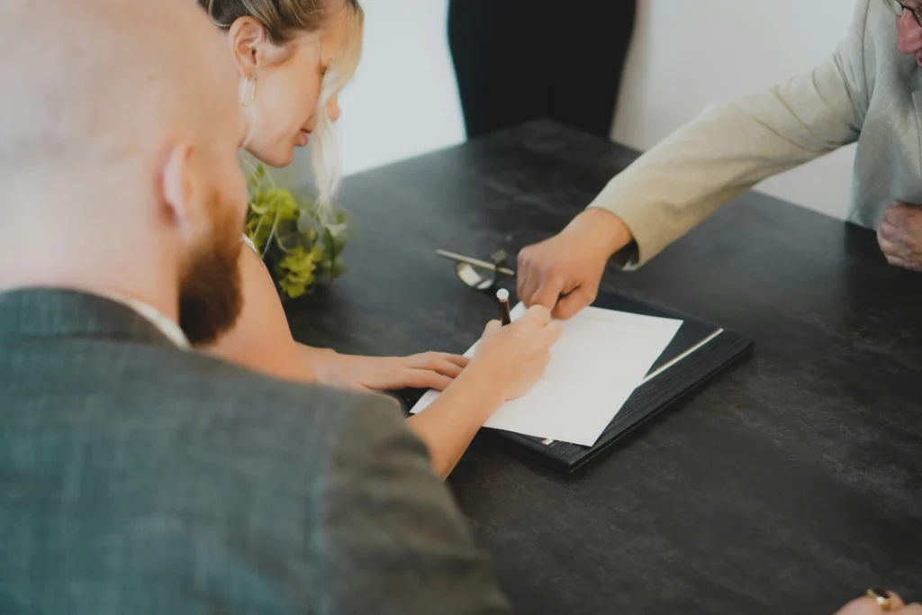 tres pessoas assinando um contrato social com papel e caneta